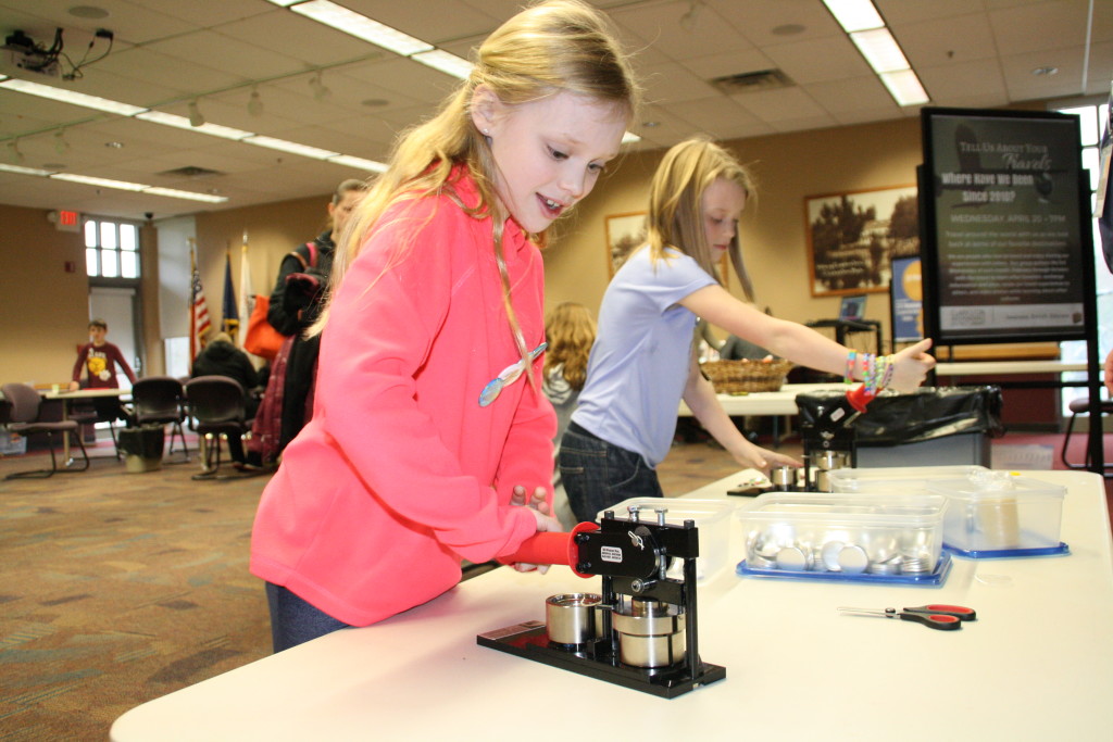 From left, sisters Anna and Aubrey Reineck use presses to make buttons at the Clarkston Independence District Library's Maker Magic event during spring break. Photo by Trevor Keiser
