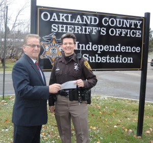 Henry Woloson presents a donation from the  David W. Elliott Memorial Foundation of Clarkston to Oakland County Sheriff’s Deputy Sharon Beltz for the Sheriff’s Benefit for the Disabled. Photo by Phil Custodio 