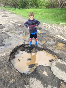 Cole Mengyan, 6, stands next to one of the potholes in front of his house. Photo provided