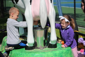 Joey and Lizzie Rickard try out milking a cow at the Oakland County Fair booth. The fair is at Springfield Oaks County Park, July 7-16.  Photo by Wendi Reardon Price